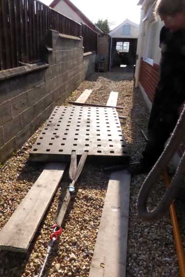 Wiching the table using scaffold poles as rollers and scaffold planks on the gravel